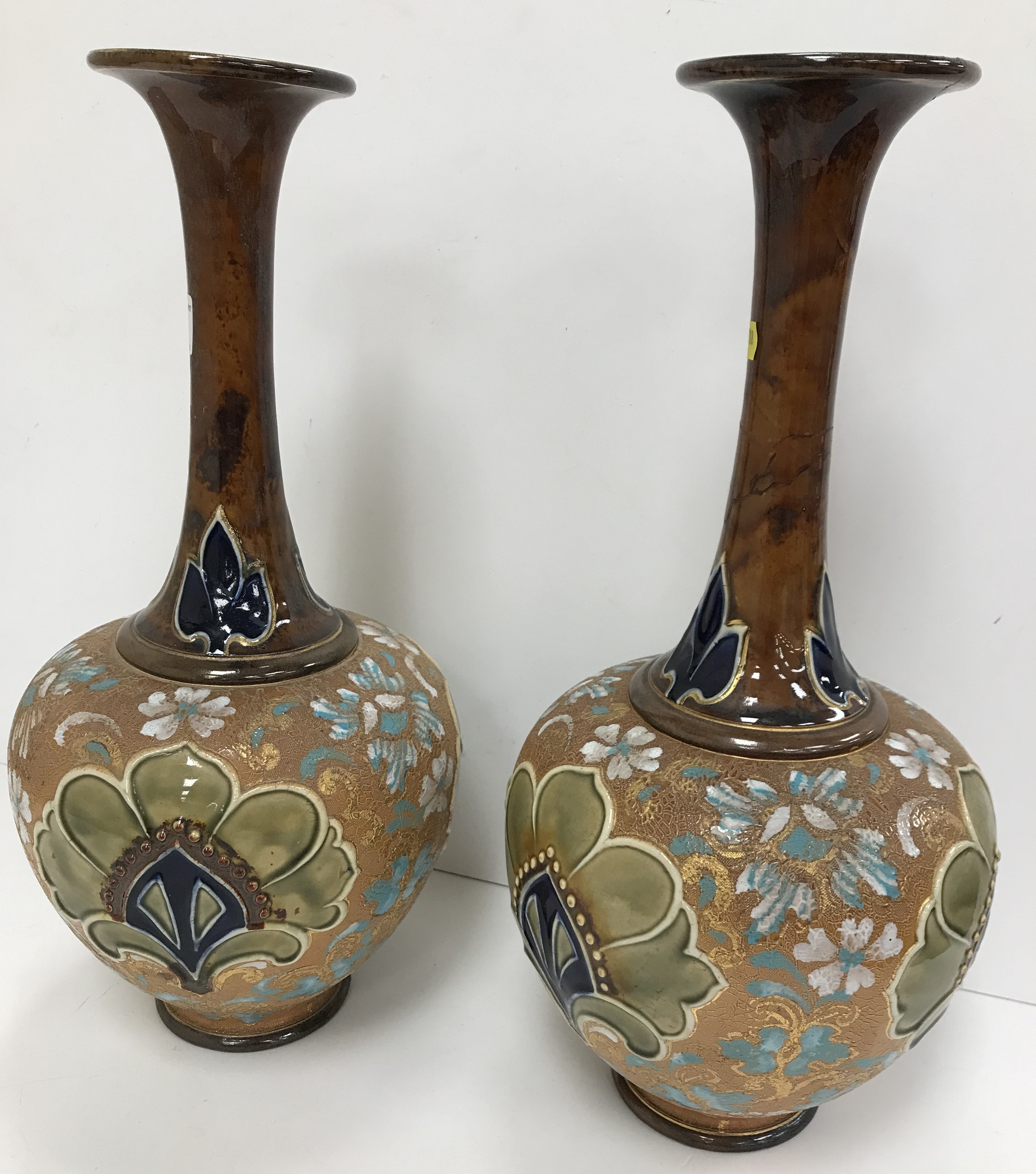 A pair of Doulton Slaters lace work and flower head relief decorated slender necked vases with