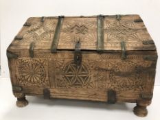 A vintage Indian Mughal dowry chest with carved medallion and brass bound decoration, raised on