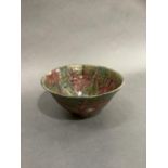 A pottery bowl heavily glazed in ox blood red and shades of green, on foot rim, 18.5cm by 9.5cm