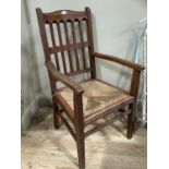 A walnut and rush seated elbow chair in the Arts and Crafts style