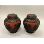 A pair of cinnabar and black jars and covers worked with rocks issuing peony within reserves of