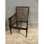 An early 19th century mahogany library chair, bergere caned back and side panels, moulded frame,