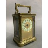 A brass carriage clock circa 1900 having a gilt face with porcelain dial and with Arabic numerals in