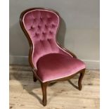 A reproduction Victorian mahogany nursing chair having encircling frame, pink buttoned upholstery
