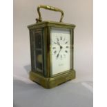 A late 19th century brass carriage clock, movement striking on a gong, the enamelled dial with black