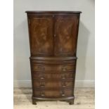 A reproduction mahogany drinks cabinet, bow fronted, having two drawers above a pull slide and