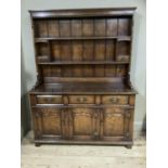 A good reproduction oak dresser and rack having a moulded cornice over planked back with shelves and