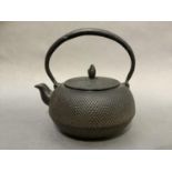 A Japanese black iron teapot of compressed circular form with disc lid and pine cone finial,