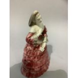 A Goldscheider pottery figure of a female in pink flounced gown holding a letter, stamped and marked