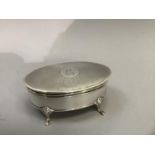 A George V silver trinket box on four pad feet, oval outline with engine turned top and blue