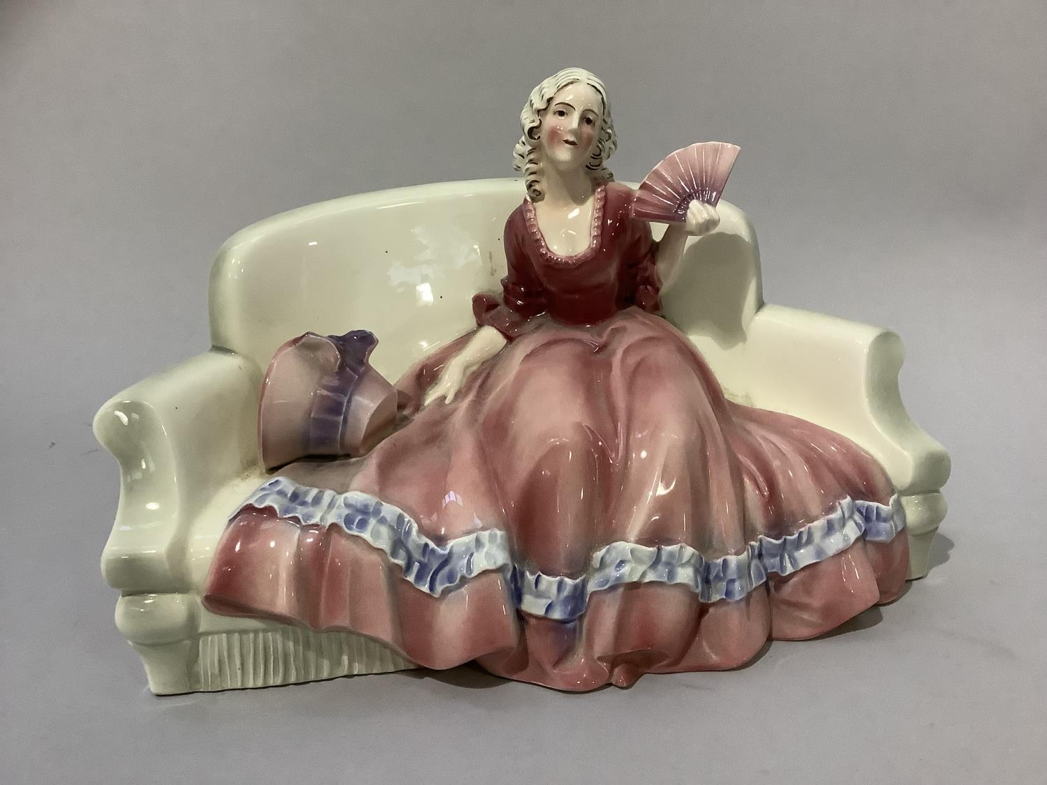 A Katzhutte figure of a lady in flowing pink gown sitting on a sofa, her bonnet beside her, model