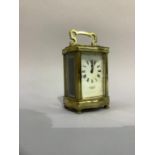 A brass cased carriage clock, the enamelled dial with Roman numerals and signed Stewart and Co