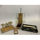A set of postal scales and weights, compass in wooden case, a set of balance scales and an Allbrit