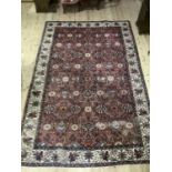 A middle Eastern carpet having a crimson ground filled with flowering vines in ivory, blue, rose and