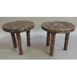 A pair of hardwood circular occasional tables each carved to the top with 'Inca' scenes and relief