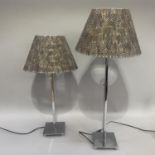 A pair of polished steel and feather table lamps with telescopic columns for height adjustment, on