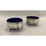 A pair of George III silver salt cellars with blue glass liner, with pierced and engraved gallery