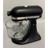 A KitchenAid Artisan food mixer with attachments in black and chrome