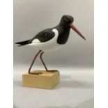 A carved wood figure of an oyster catcher on wood block