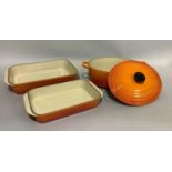 A Le Creuset orange enamel two-handled casserole pan and cover, 37cm over handles and two lasagne