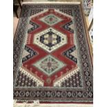 A Caucasian rug, the red field having three hooked medallions with further hooked geometric shapes