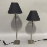 A pair of chrome table lamps of graduated size, on square bases, and having adjustable heads with