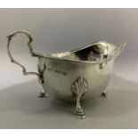 A silver sauceboat by J R Ogden of Harrogate with three pad feet, C scroll handle and beaded rim,