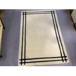 A cream wool rug with twin black line border, 290cm x 200cm