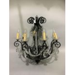 A pair of eight light candelabra with black metal scrolling arms and leafage, glass sconces,