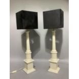 Two white pottery column table lamps on square bases and with black square shades, overall height