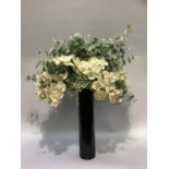 A display of faux orchid, gypsum and foliage in a tall black plastic vase, overall height
