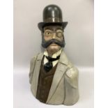 A head and shoulder bust of a Phileas Fogg with bowler hat, monocle and handle bar moustache,