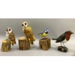 Two painted wood owls perched on wood blocks, a blue tit and a robin