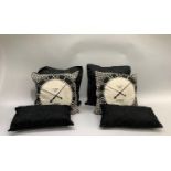 Cushions including two beige and black clock face cushions, a pair of black silky cushions and two