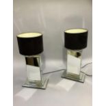 A pair of mirrored table lamps of rectangular form, on stepped base and with black drum shades, 57cm