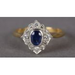 A SAPPHIRE AND DIAMOND CLUSTER RING in 18ct yellow and white gold, the oval faceted sapphire