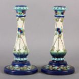 A PAIR OF BURMANTOFT FAIENCE CANDLESTICKS, enamelled and incised with entwined flowering tendrils