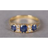 A GEORGE V SAPPHIRE AND DIAMOND RING in 18ct gold, the graduated oval faceted sapphires