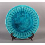 A BURMANTOFTS FAIENCE CHARGER of turquoise glaze incised with opposing peacocks to the centre within
