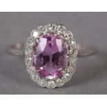 A PINK TOURMALINE AND DIAMOND CLUSTER RING in platinum, c.1950, the oval faceted tourmaline claw set