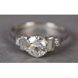 A DIAMOND RING in platinum c.1950, the brilliant cut principal stone claw set and flanked by four