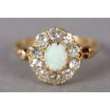 AN EDWARD VII OPAL AND DIAMOND CLUSTER RING in 18ct gold, the oval cabochon stone claw set within
