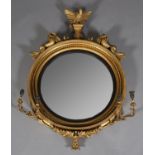 AN 18TH CENTURY GILTWOOD AND GESSO CONVEX WALL MIRROR having an eagle and foliate cresting flanked