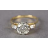 A SINGLE STONE DIAMOND RING in 18ct gold, the certified brilliant cut stone claw set and flanked