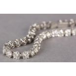 A DIAMOND TENNIS BRACELET, the brilliant cut stones claw set in line in white metal (tests as