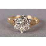 A DIAMOND CLUSTER RING the brilliant cut stones claw set within a circular outline flanked by