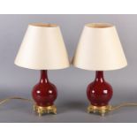 A PAIR OF FRENCH SANG DE BOEUF AND GILT METAL TABLE LAMPS, of bottle shape, on four feet with