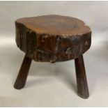 AN EARLY 19TH CENTURY YEW-WOOD STOOL, the seat rough cut from the tree, the surface polished, on