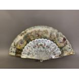 A large and showy mother of pearl fan, the wide sticks gilded and brightly painted with flowers,