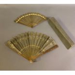 A c.1905 pale horn fan, lightly gilded, with olive green silk leaf, cut away in places to reveal